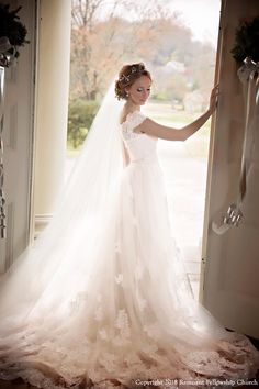 a woman in a wedding dress is standing by the door