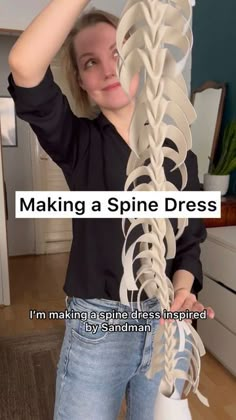 a woman holding up a large skeleton model with text reading making a spine dress i'm making a giraffe dress inspired by sandman