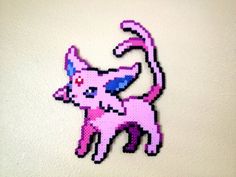 a pink cat made out of perler beads on a white wall in the shape of a pixel