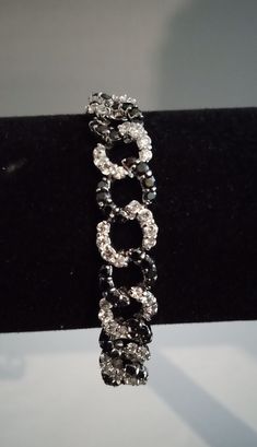 A glittering piece of elegance at a reasonable price. Perfect for those occasional events where glamour is a necessity, but cost is an issue. This bracelet will stand up to the best of them with its intertwined circles of white and black well cinched stones. The bracelet measures approx. 7 ½   inches and weighs 0.88 oz. The circles are 1/2  inches in diameter. .Please look at my pictures carefully as they are an important part of the description. Silver Crystal Bracelet With Sparkling Stones For Party, Silver Rhinestone Bracelets For Party, Silver Bracelets With Rhinestones For Party, Sparkling Adjustable Tennis Bracelet For Party, Adjustable Sparkling Jewelry For Evening, Elegant Silver Bracelets With Rhinestones, Sparkling Adjustable Jewelry For Evening, Silver Crystal Bracelet With Rhinestones For Formal Occasions, Adjustable Diamond Accents Bracelets For Party