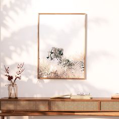 a framed photograph of two cheetah cubs on a wall next to a vase with flowers