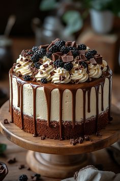 a chocolate cake with white frosting and blackberries on top is sitting on a wooden platter