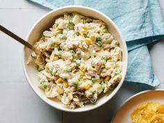 a white bowl filled with chicken salad next to an orange and green potato wedges