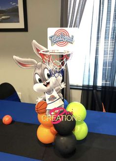 a table with some balls and a basketball hoop on it's head, in front of a window