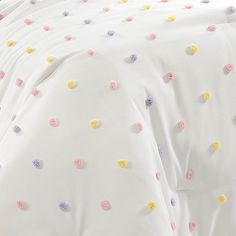 a bed with white sheets and colorful polka dots on it