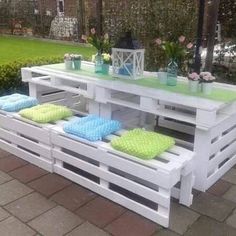 an outdoor table made out of pallets with pillows on the bottom and green cushions