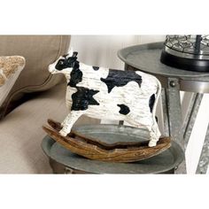 a cow figurine sitting on top of a table next to a pillow and chair