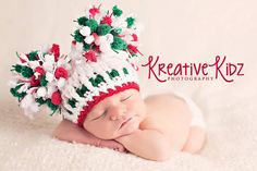 a newborn baby wearing a crocheted christmas hat with pom - poms