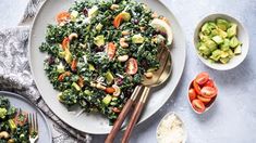 a white plate topped with salad next to bowls of vegetables