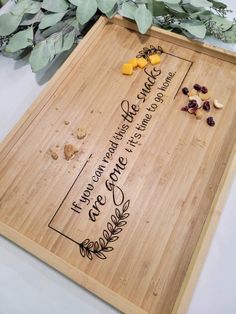 a wooden cutting board with writing on it and some dried flowers in front of it