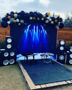 an outdoor stage set up for a concert with blue lights and speakers on the side