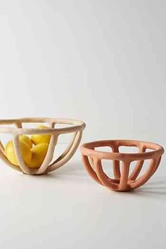 two bowls with fruit in them sitting on a table next to each other and one has an orange inside the bowl