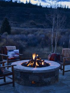 an outdoor fire pit with chairs around it