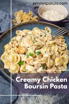 creamy chicken boursin pasta in a blue bowl with a fork on the side