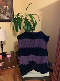 a purple and black blanket sitting on top of a chair next to a potted plant