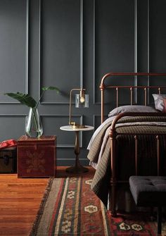 a bed room with a neatly made bed next to a rug and a lamp on a table