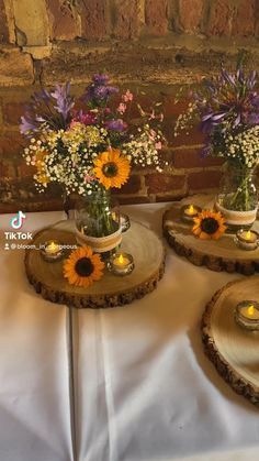 three vases with sunflowers and candles on wooden slices for centerpieces