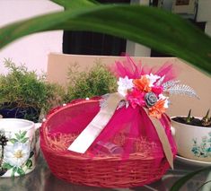 a basket sitting on top of a table next to two cups and saucers filled with flowers