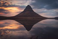 a mountain is reflected in the water at sunset