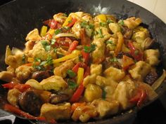 a pan filled with chicken and vegetables on top of a stove