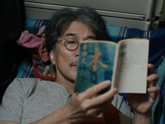 an old man reading a book while laying in bed