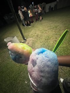 a person holding two different colored items in their hands while standing on the grass at night