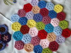 a crocheted patch is laying on top of a white blanket with flowers in the background