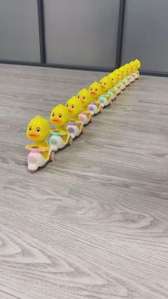 a row of yellow rubber ducks sitting on top of a wooden floor next to each other