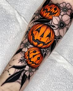 a tattoo with three pumpkins and flowers on it's arm, all decorated in black and white