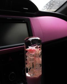 a blender filled with pink liquid sitting on top of a car dashboard