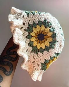 a hand holding a crocheted doily with a sunflower on it