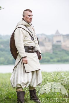 a man dressed in period clothing standing on grass