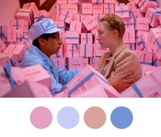 a man and woman sitting next to each other in front of stacks of pink boxes