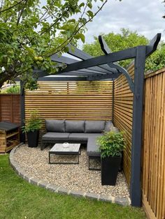 an outdoor seating area in the middle of a yard with wooden fence and planters