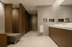 a large bathroom with wooden cabinets and white tile flooring, along with a bench in the middle