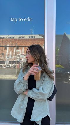 a woman holding a drink in front of a window with the words tap to edit on it