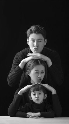 three people sitting on top of each other in front of a black and white photo