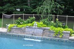 an outdoor swimming pool surrounded by greenery and fenced in area with water feature