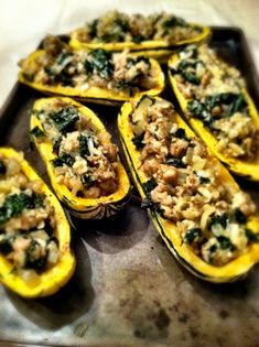 stuffed squash with stuffing and spinach on a baking sheet ready to be cooked in the oven