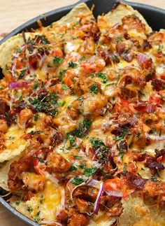 a pizza topped with meat, cheese and veggies sitting on top of a pan