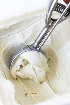 a scoop of ice cream in a white bowl with a red handled mixer on it