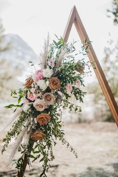 a wedding arch decorated with flowers and greenery for an outdoor ceremony in the mountains