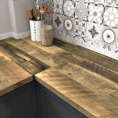 a wooden counter top in a kitchen next to a vase with utensils on it