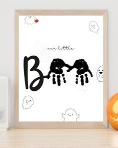 a framed poster with the word boo written in black on it next to an orange pumpkin