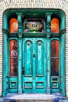 an old green door in front of a brick building with ornate glass and wood trim