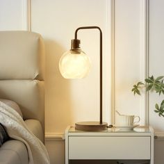 a table lamp sitting on top of a white couch next to a potted plant