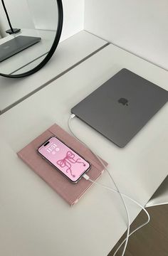 an apple laptop computer sitting on top of a white desk next to a pink case