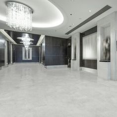 an empty room with chandelier and mirrors on the walls, in front of two elevators