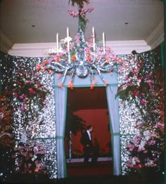 a man standing in front of a doorway decorated with christmas lights and garland on the wall