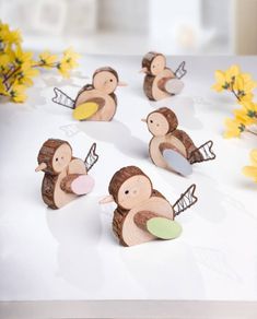 some little wooden animals sitting on top of a white table with yellow flowers in the background